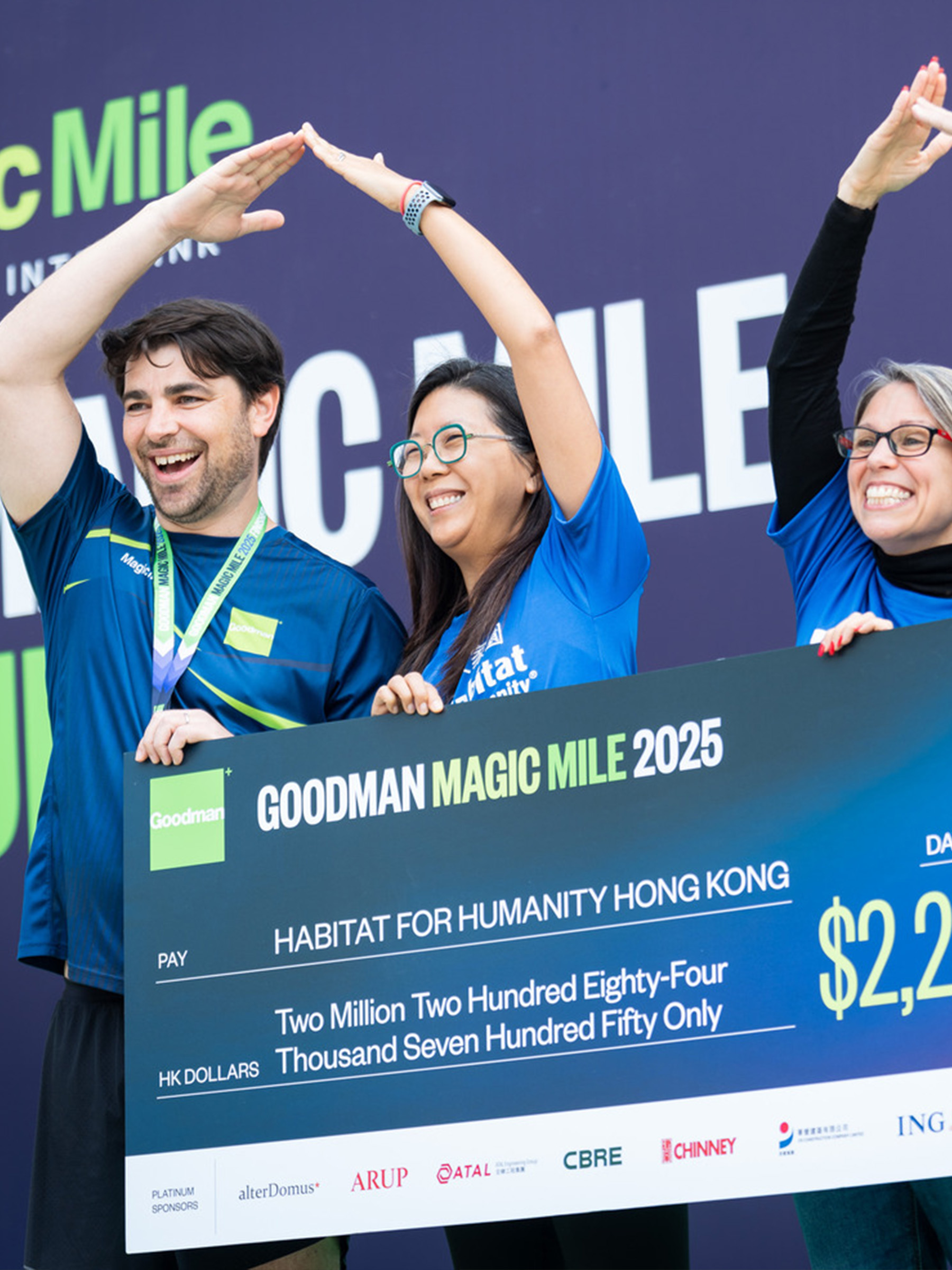 Magic Mile volunteers smiling together with the donation cheque from Goodman after completing the charity run